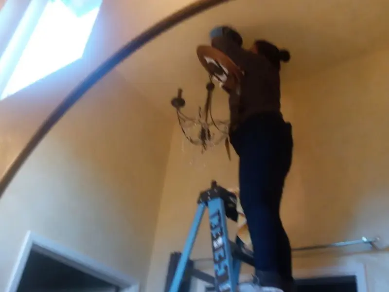 Electrician installing a chandelier in a Crete residence